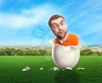 Strange man hatched out of the egg on the meadow