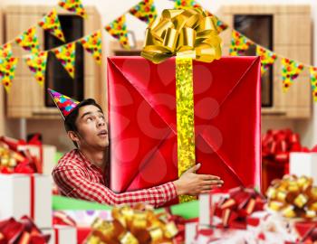 Birthday man holding a big gift in deecorated room