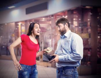Woman taking money from husband's purse in the shopping mall