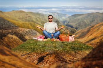 Man on the picnic alone sitting in the lotus position in the mountains