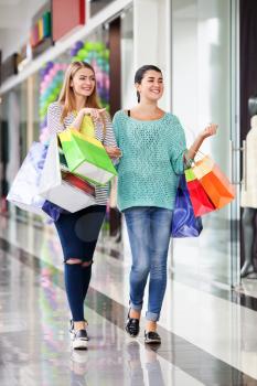 Young happy women with bags in the shopping mall