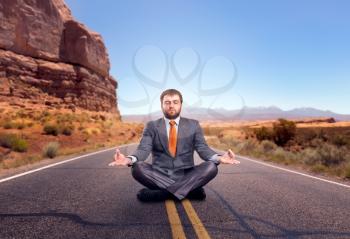 Businessman meditating sitting on the road