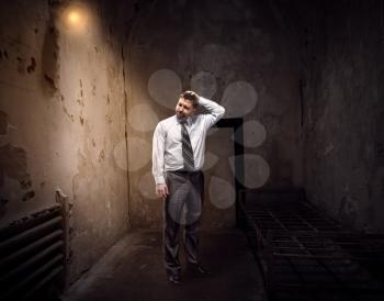 Businessman standing in an old dark jail
