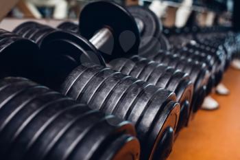 Heap of black dumbbells with weight plates on the floor