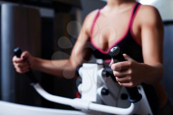 Close up of girl's hand training on the sport machine in the gym