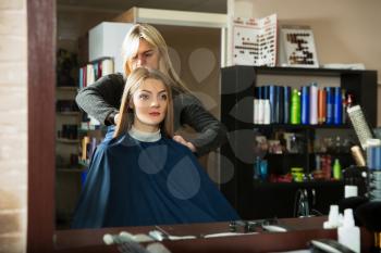 Young woman in front of the mirror prepares for hairdressing 