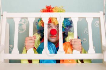 Punished clown sits under a bench. Birthday party entertainment.