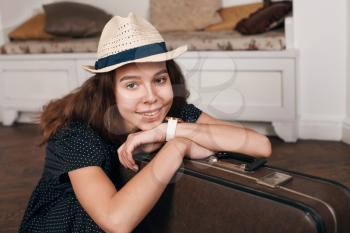 Portrait of young smiling woman in white hat and black dress with suitcase. Journey concept in retro style.