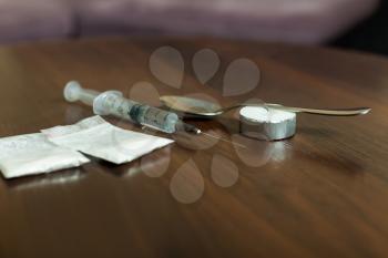 Drug, spoon and syringe on a table.  Addict hard drugs collection on wooden table.