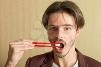 Young man trying to eat tablet using chopsticks. Traditional japanese tableware.
