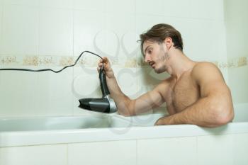 Depressed man preparing to commit suicide with hairdryer in bathroom. Commit suicide with electricity.