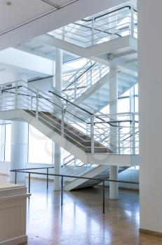Marble floor and metal staircase in modern building with white interior.