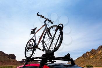 Bike transportation on the roof of a car. Blue sky and mountains on the background.