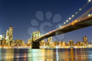 Illuminated Brooklyn bridge and manhattan view from hudson river at night time, New York City USA