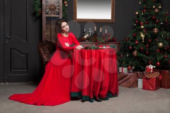 Young woman waiting in vintage restaurant. Glamour female in red dress, romantic evening.