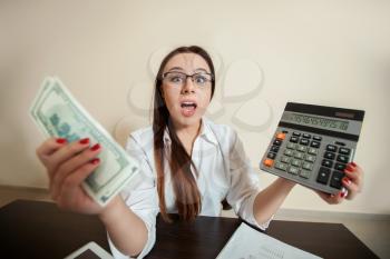 Female accountant holding dollars and calculator in her hands. 
