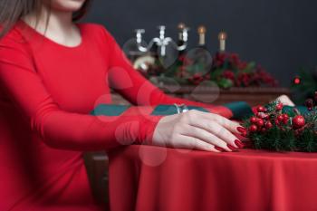 Young female in red dress, hands closeup. Woman sitting at the table in restaurant with rich interior.