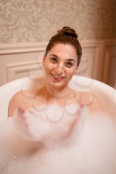 Nude woman relaxation in bath with soap top view.