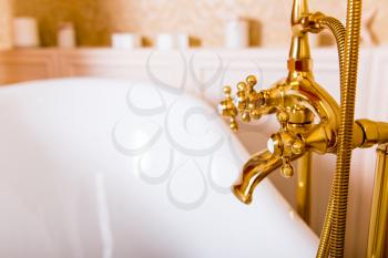 Rich gold faucet and white bath in the bathroom. Luxury sanitary equipment