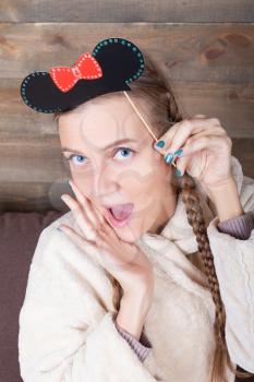 Young cute girl with funny hairstyle on a stick, wooden background. Fun photo props and accessories for shoots