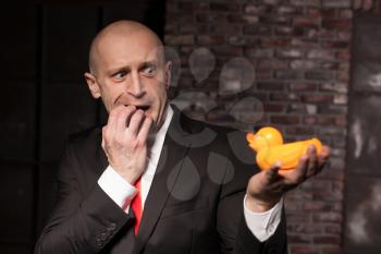Scared contract murderer in suit and red tie shows his fears and secrets. Afraid special agent looks at little toy duck in hand. Frightened hired murderer wallpaper or background