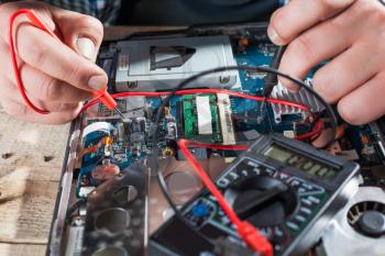 Male engineer hands diagnostics laptop with multimeter closeup view. Electronic devices repairing technology