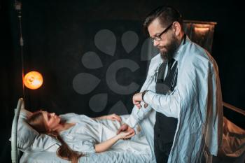 Male doctor measures the pulse of young sick woman in the hospital. Illness of female patient in clinic, health recovery and treatment