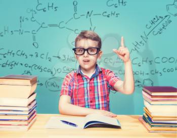 Scientist little boy gets knowledge in the school library. Pupil in glasses against books