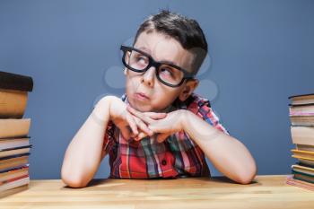 Little schoolboy learns homework at the desk in classroom. Pupil in glasses gets knowledge