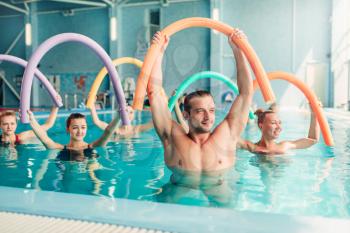 Aqua aerobics exercises, women with male trainer, indoor swimming pool.