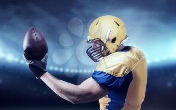 American football player with ball in hands, on sport arena. National league