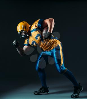 American football offensive player with ball in hand, national league, black background. Contact sport