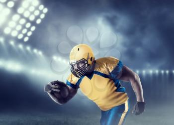 American football player with ball in hands, on sport arena. National league