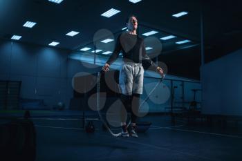 Active man on training, workout with rope in gym. Energy exercises in sport club