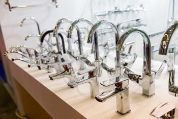 Rows of new chrome faucets in plumbing shop, closeup. Sanitary equipment