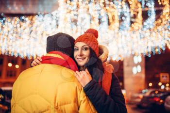 Winter evening, love couple hugs on the street. Man and woman having romantic meeting, happy relationship