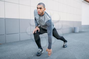 Athlete doing stretching exercise before running. Jogger on morning fitness workout. Runner in sportswear on training outdoor