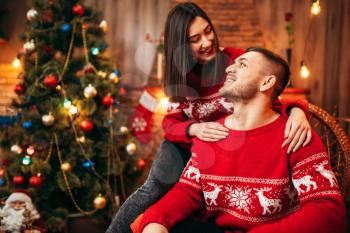 Happy love couple celebrate christmas holidays. Xmas celebration, cheerful man and woman together, fir-tree with decoration on background