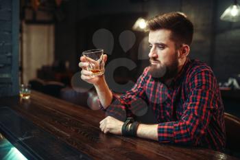 One man sitting at the bar counter and drink alcohol beverage. Male person in pub