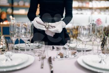 Waitress with a bottle of champagne, table setting. Serving service, festive dinner decoration