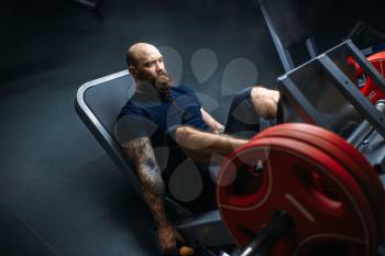 Strong athlete on exercise machine with barbell, training in gym. Bearded man on workout in sport club, healthy lifestyle