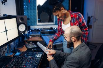 Sound operator and female singer at remote control panel in audio recording studio. Musician at the mixer, professional music mixing