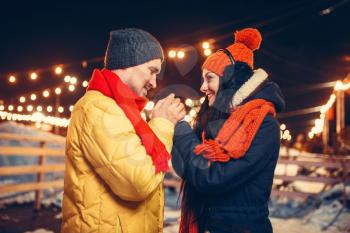 Winter evening, love couple warm hands outdoors. Man and woman having romantic meeting on city street with lights