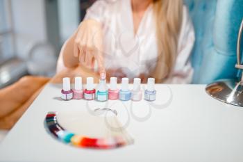 Female customer choosing nail varnish in beauty shop. Professional manicure and pedicure service, hands and legs treatment, client in beautician salon, woman at the manicurist