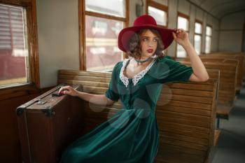Beautiful woman in retro train, old wagon interior. Railroad voyage. Vintage journey