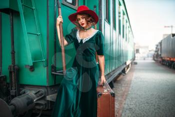 Woman in red hat against old railway wagon. Retro train. Railroad journey