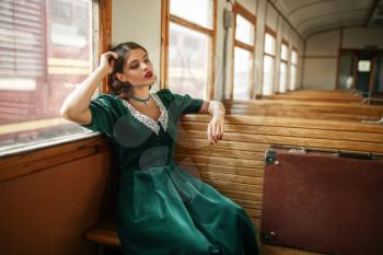 Female traveler in retro train, old wagon interior. Railroad voyage. Vintage journey