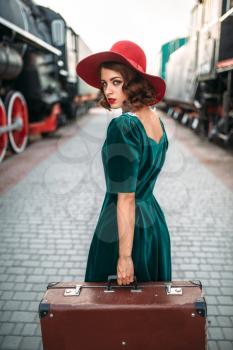 Young old-fashioned woman travels on retro train. Old locomotive. Railway platform, railroad journey