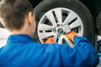 Mechanic unscrews car wheel, tire service. Automobile repair, vehicle maintenance