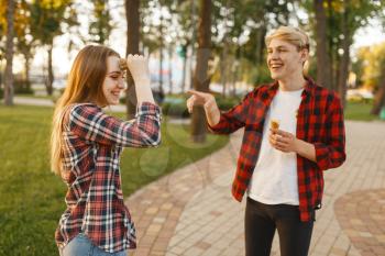 Love couple having fun with ice cream in summer park. Young man and woman leisures with ice-cream, romantic walk together outdoor